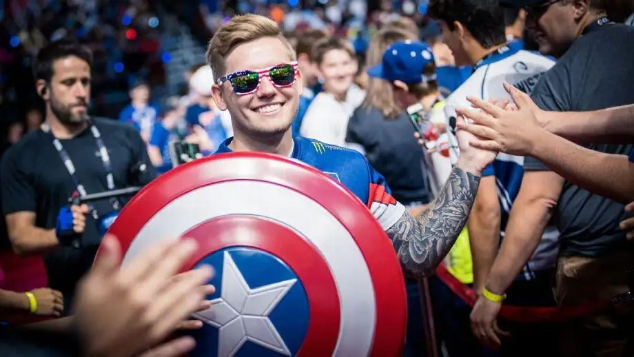 nitr0 wearing sunglasses with the United States flag, holding a captain america shield and high-fiving the audience.